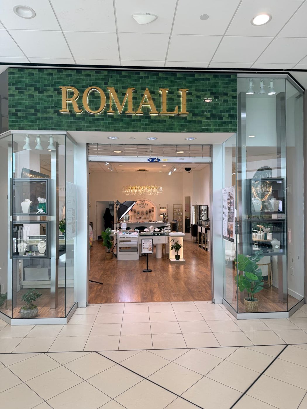 The ROMALI storefront at Promenade Shopping Centre: gold ROMALI lettering on green tile above a glass entrance with jewelry display cases.