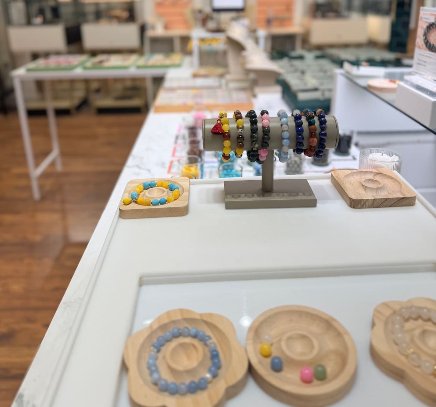 Wooden bead design trays and a stand of beaded bracelets on the ROMALI Bead Bar counter.
